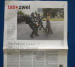 Bild von einer Tageszeitung Seite von der taz. Oben ist ein Bild von einer jungen Schwarzen Frau im Kleid, die bei einer Protest auf der Strasse steht, ganz ruhig und selbstbehauptend, und drei Bullen in schwarzen Kampfausrüstung rennen ihr entgegen, um sie festzunehmen